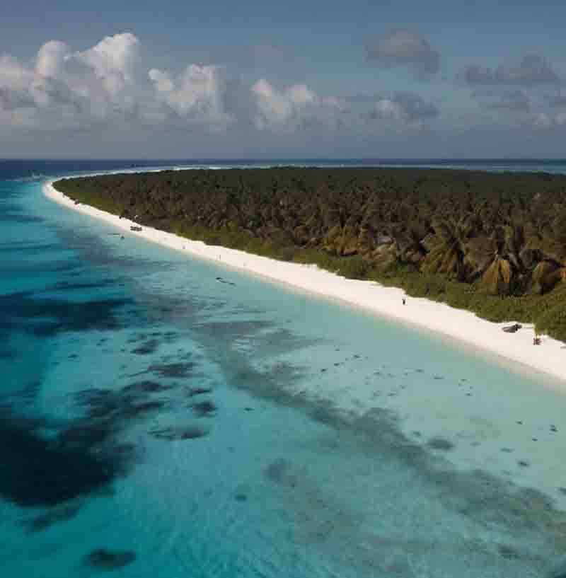 Luftaufnahme eines weißen Sandstrandes und einer kleinen Insel im Indischen Ozean.